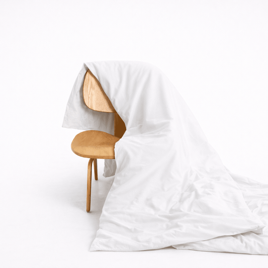 Capa de edredom em bambu branco drapeada em cadeira de madeira, mostrando textura de tecido macio e design de fecho com botões ocultos