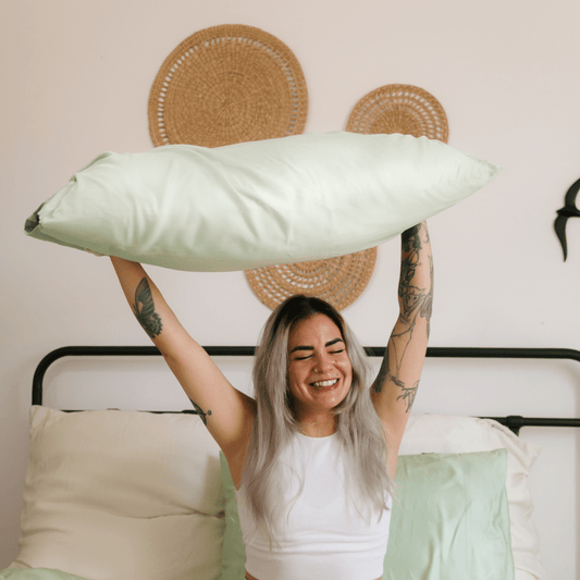 Mulher a segurar roupa de cama de bambu branca confortável numa cama