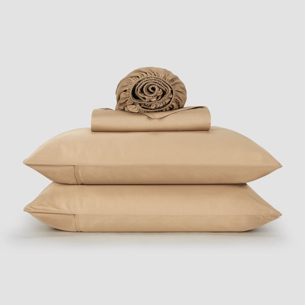 Mulher na cama com lençol e almofadas de bambu rosa – roupa de cama macia, respirável e sustentável