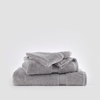 Conjunto de toalhas de bambú cinzento empilhadas sobre fundo branco, incluindo toalhas de rosto, mão e banho