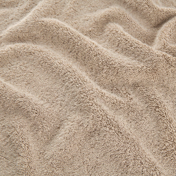 Conjunto de toalhas em bambu bege mostrando detalhe de textura suave de toalhas de rosto, mão e banho