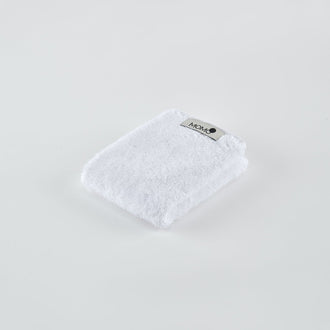 Toalha de bambu branca com etiqueta Momo Cotton em fundo claro, vista angular