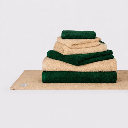 Conjunto de toalhas Momo Cotton Wabi Sabi empilhadas em creme e verde floresta sobre fundo branco
