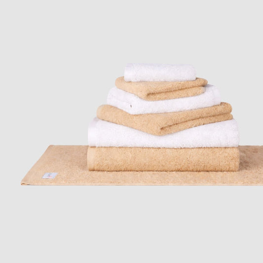 Conjunto de toalhas de algodão bege e branco da Momo Cotton em fundo neutro