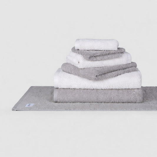 Wabi Sabi towel set by Momo Cotton displayed in stacked gray and white towels on a folded base towel against white background