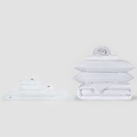 Conjunto completo de lençóis brancos e coleção de toalhas Momo Cotton exibido em fundo neutro