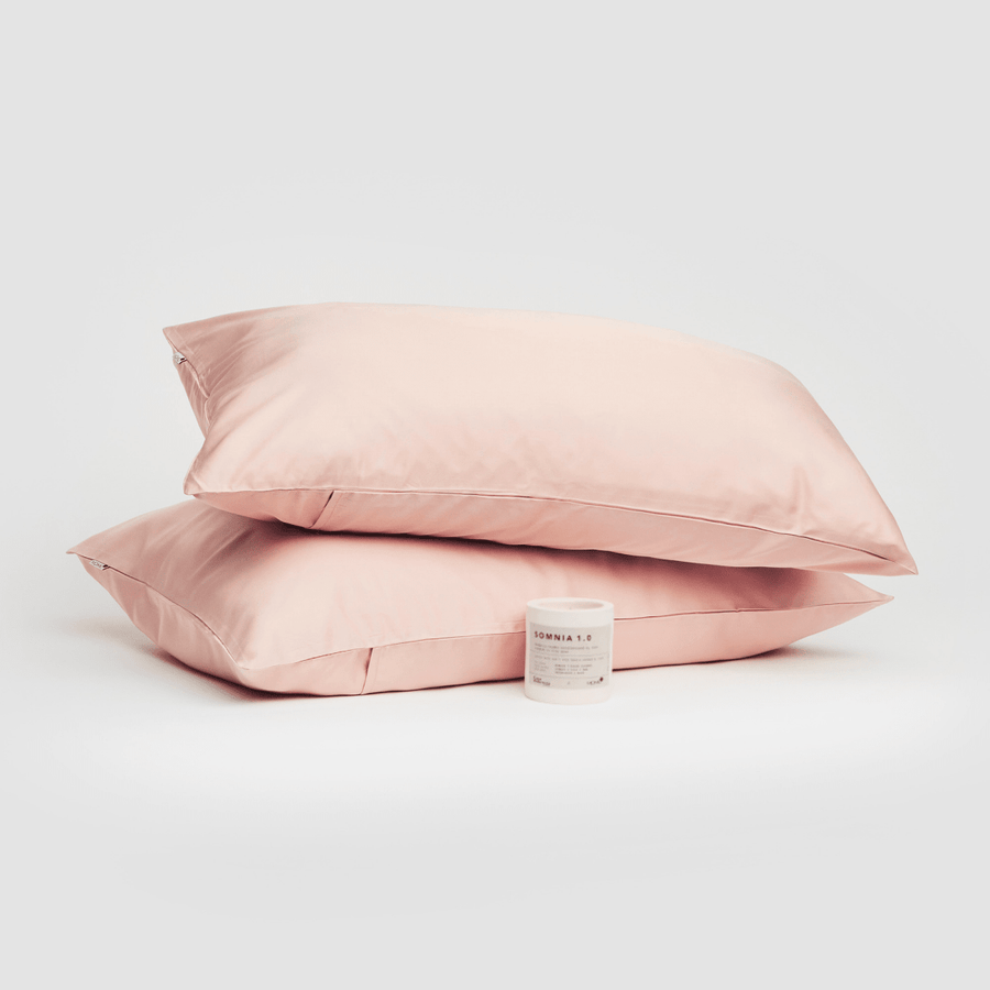 Par de fronhas de algodão rosa apresentadas com produto Somnia 1.0 em fundo branco