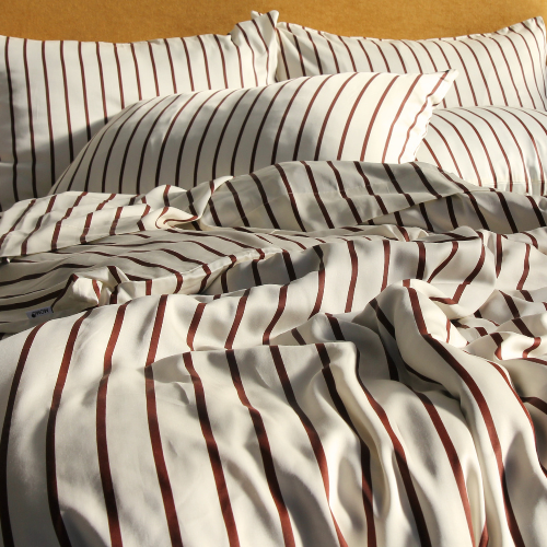 Jogo de cama completo de bambu com padrão de riscas vermelhas, apresentando fronhas e lençóis dobrados na cama