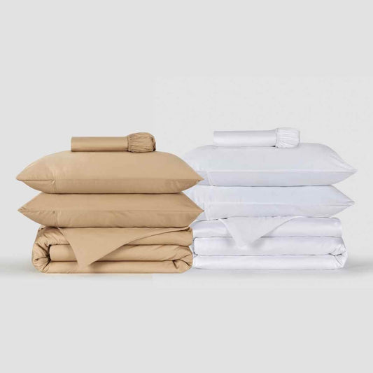 Conjuntos de roupa de cama bege e branco empilhados, com almofadas e capas de edredão Momo Cotton