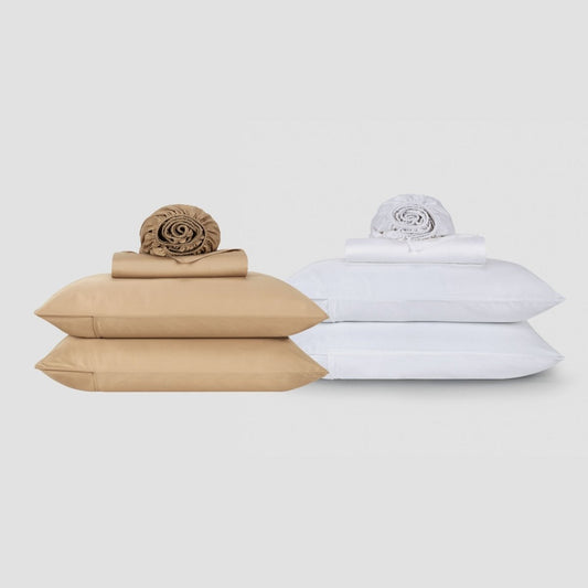 Conjuntos de lençol de algodão Momo bege e branco empilhados com roupa de cama e almofadas enroladas em fundo neutro