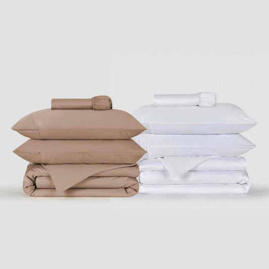 Conjuntos de capa de edredão bege e branco empilhados exibindo roupa de cama dobrada com almofadas e lençóis da Momo Cotton