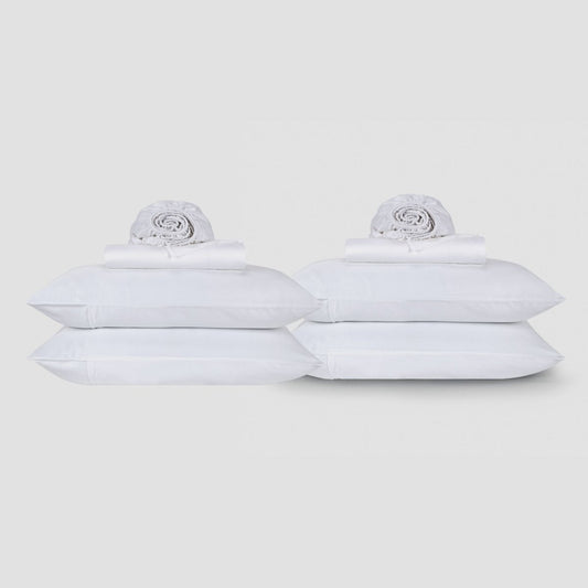 Dois lençóis brancos de algodão empilhados com roupas de cama enroladas sobre fundo neutro pela Momo Cotton