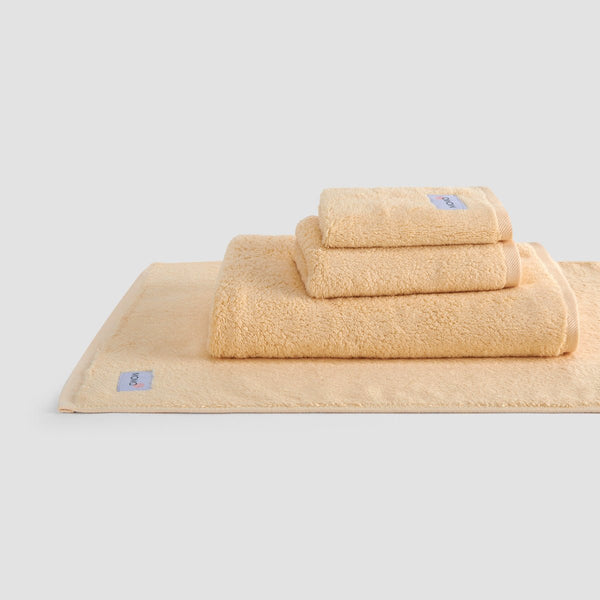 Conjunto de toalhas de bambu bege Wabi-sabi em pilha, com toalhas de rosto, mão e banho com marca